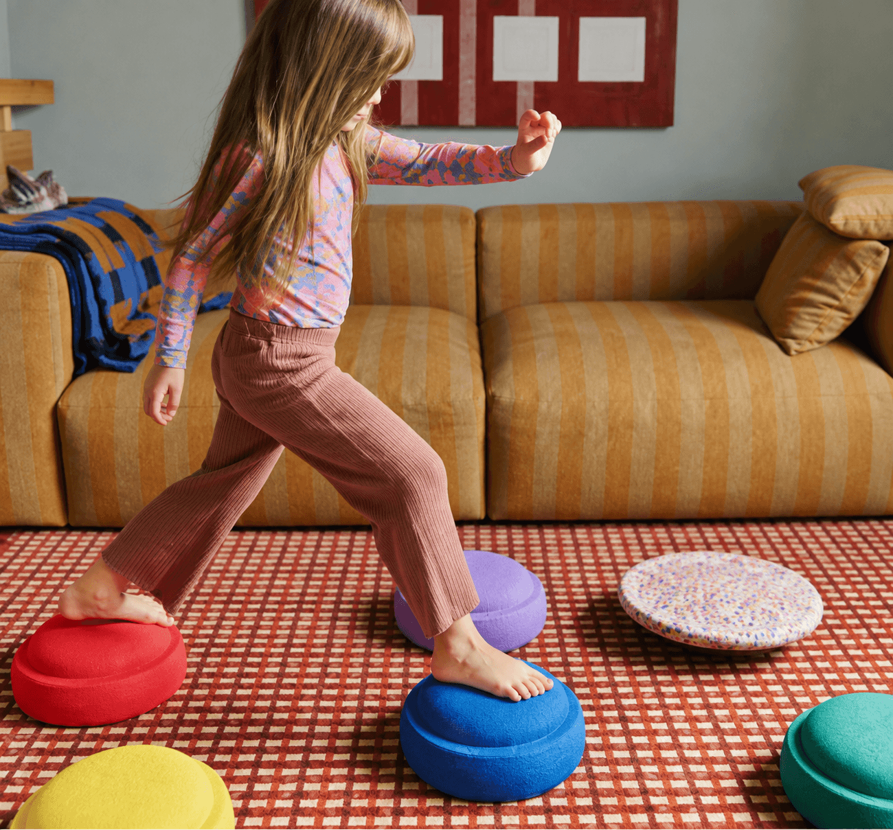 Niña saltando entre plataformas de equilibrio en una sala de juego